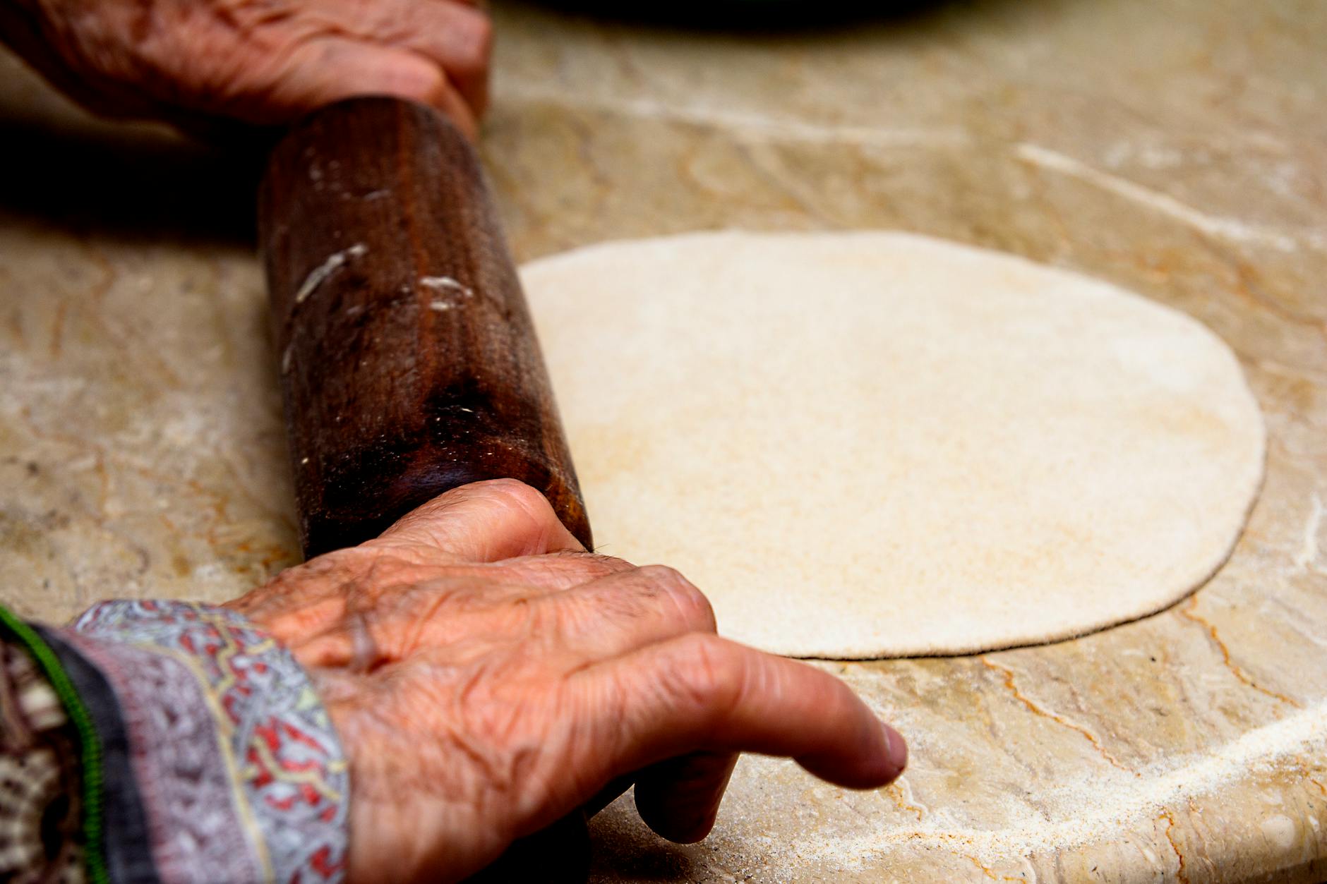 a person holding brown wooden rolling pin